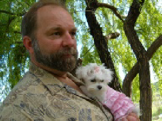 Barb's husband holding their first Maltese, Pink, dressed in a little pink outfit under a willow tree—where the Storybook Maltese journey began